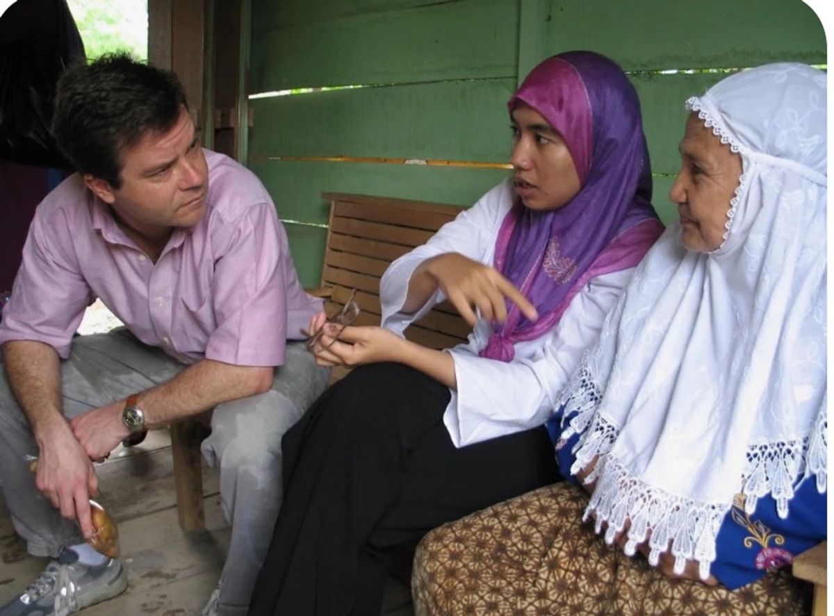 Alex Counts speaks intently with two women wearing traditional dress.